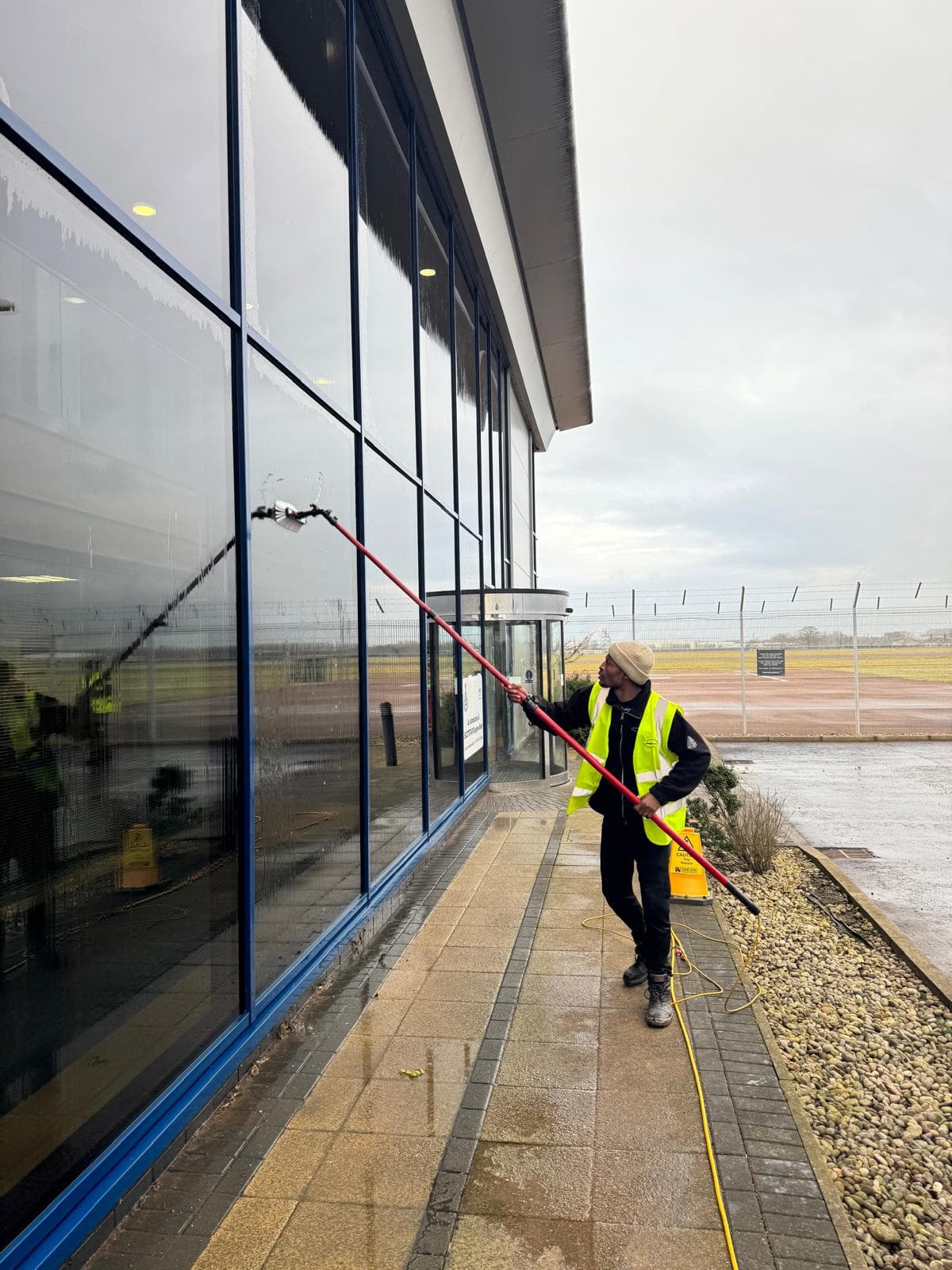 Water-fed pole on full-height glazing